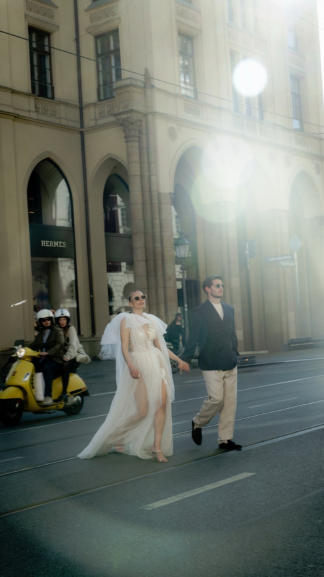 Couple crossing Maximilianstraße in Munich — Vespa and Hermès backdrop