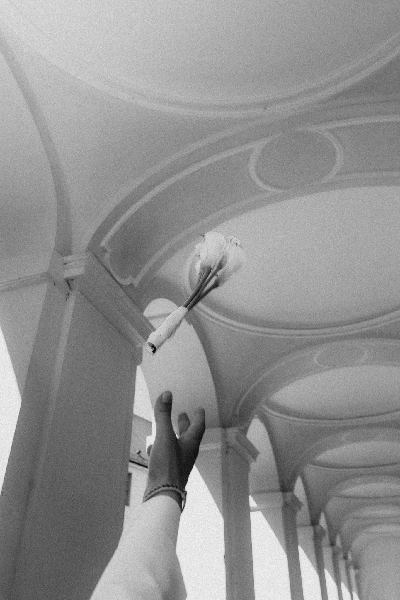 Bouquet toss under the castle arcades, black and white