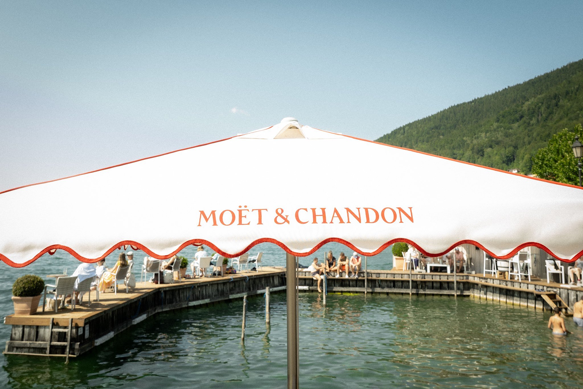 A parasol shades the lake deck at the Clubhaus Tegernsee on a summer day.
