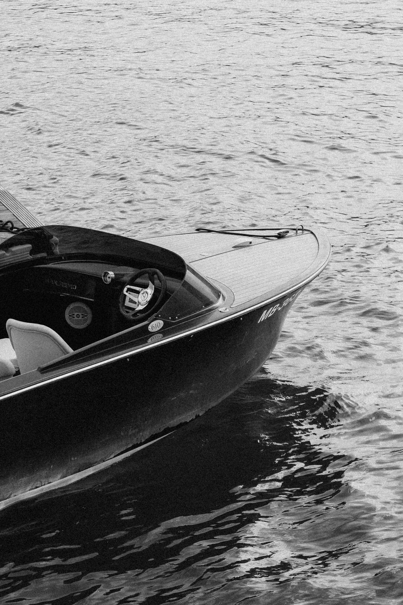 A vintage wooden boat floats on Lake Tegernsee in black and white.