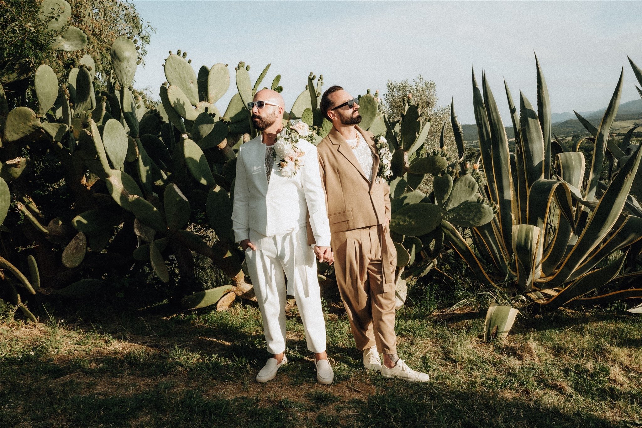 Tony and Patryk in their wedding suits among the cacti in Tuscany.