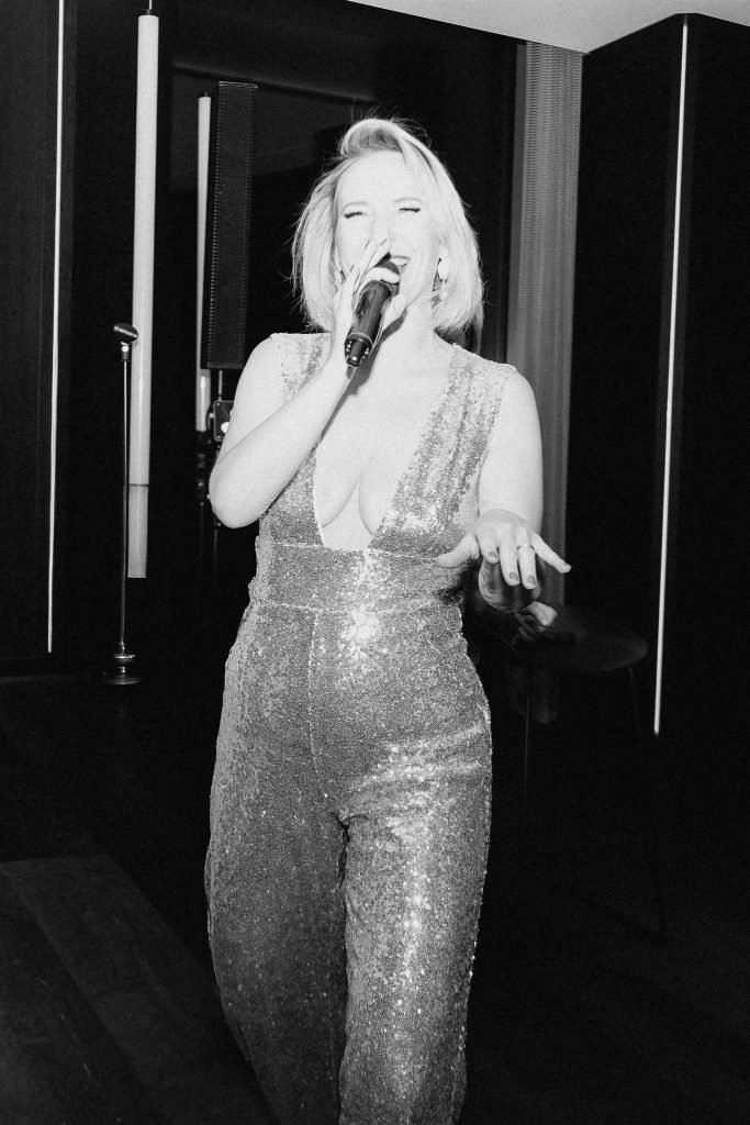 Singer in a sequin jumpsuit with microphone performing at a wedding in Munich.