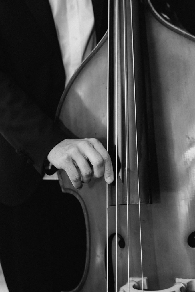 Black and white detail of a double bass player during a wedding celebration.