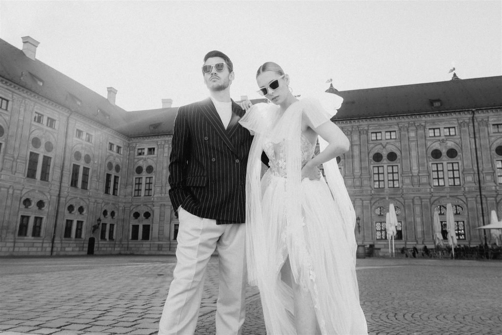 Couple in wedding attire standing in the courtyard of the Munich Residenz, black and white.