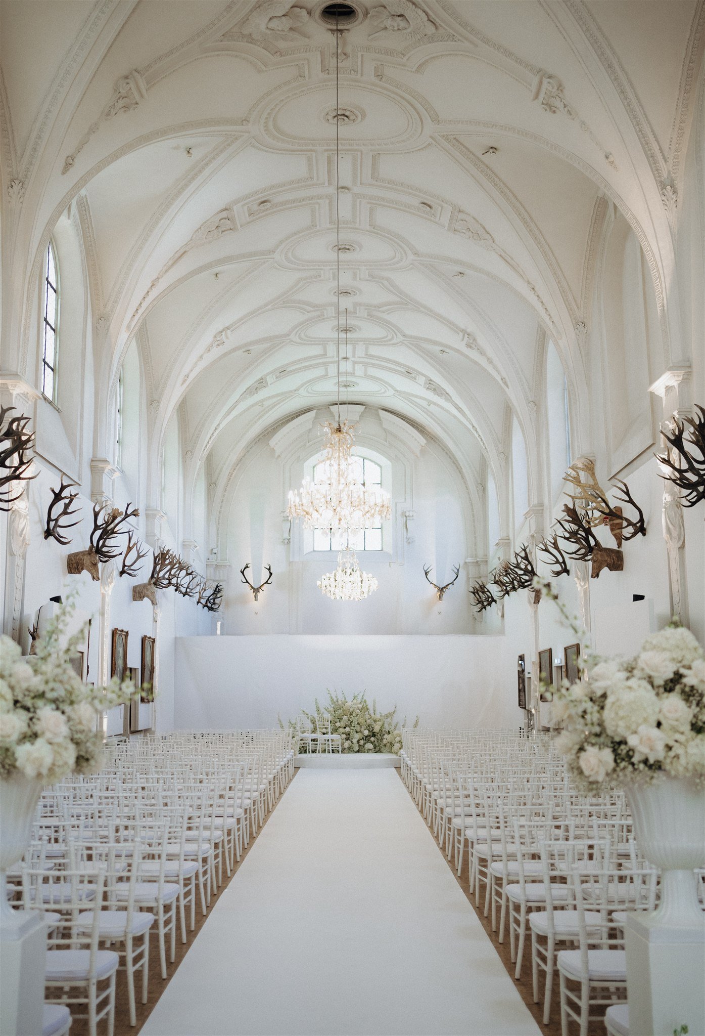 Empty ceremony aisle at Venue 1315 framed by white floral arrangements.