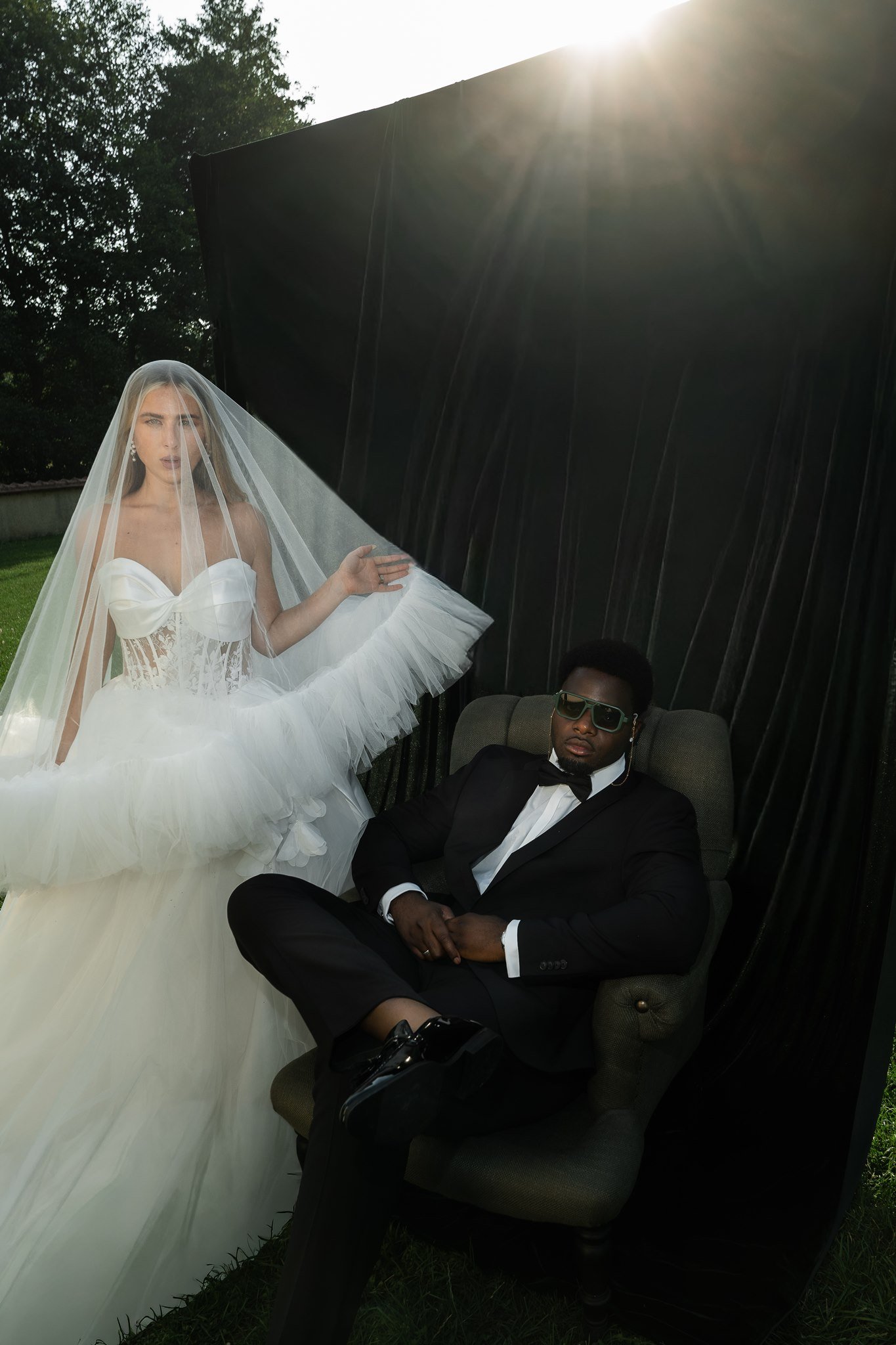 Bride with veil and groom in sunglasses in the garden of Schloss Duttenstein
