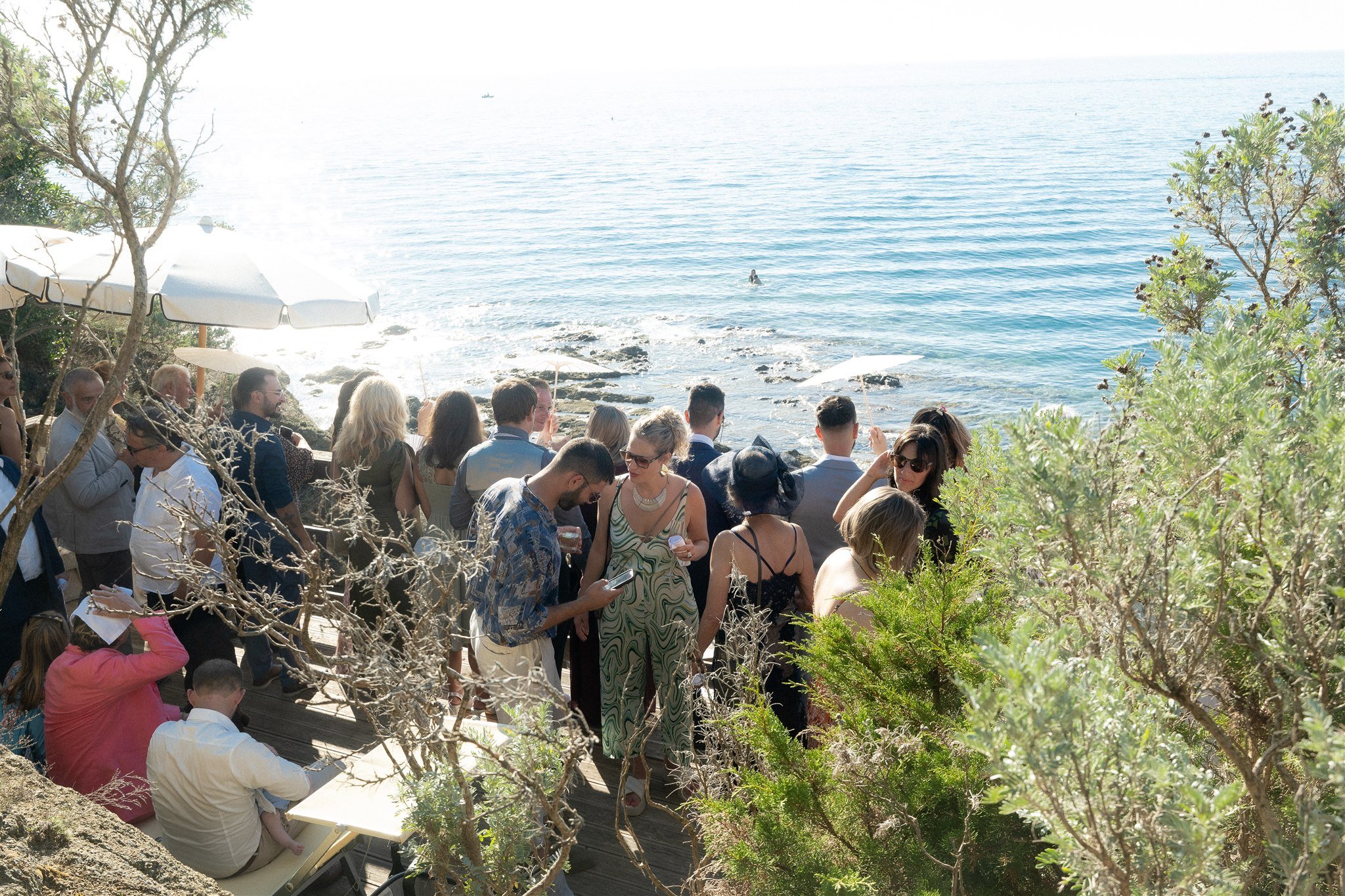 Wedding guests at the seaside aperitivo terrace above the rocks