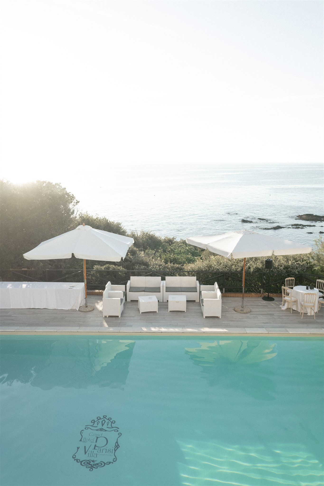Poolside lounge with white parasols above the Mediterranean sea
